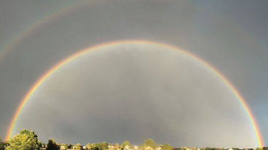 Riane Coleman poses beneath a beautiful double rainbow