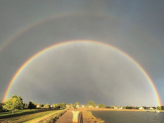 Riane Coleman poses beneath a beautiful double rainbow